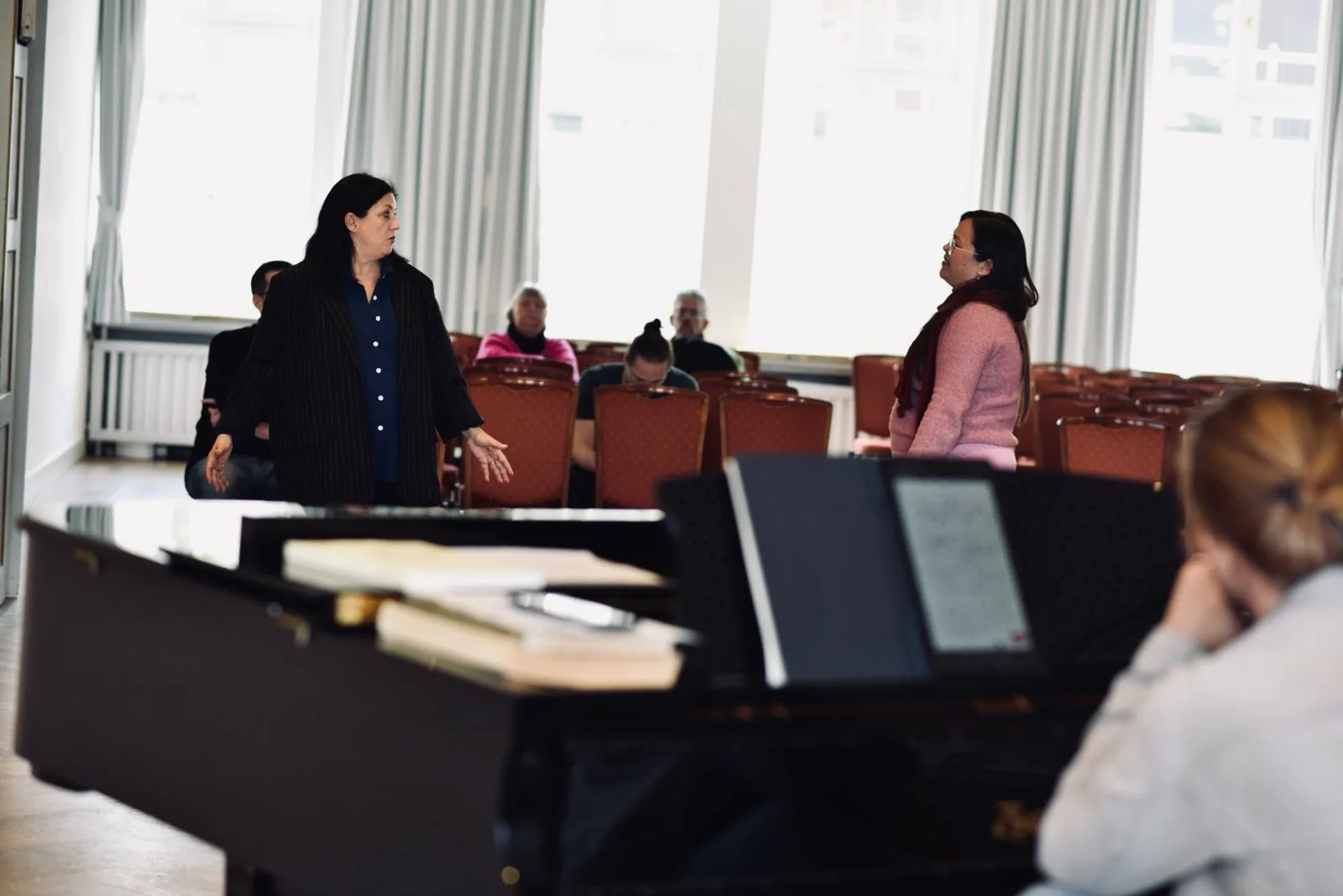 Jasmin Solfaghari mentort eine Sängerin am Klavier vor Publikum